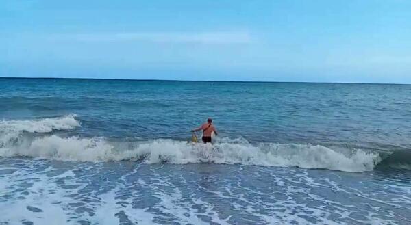 Un agente de la Policía Local de Villajoyosa rescata un bañista entre fuerte oleaje del mar en la playa del Bol Nou 